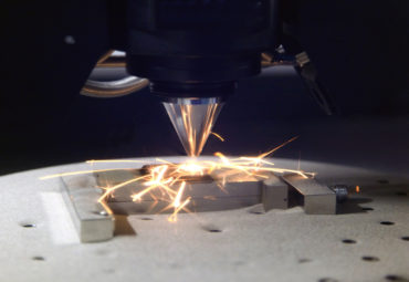 Detailed close-up of 3D printer printing a metal piece.