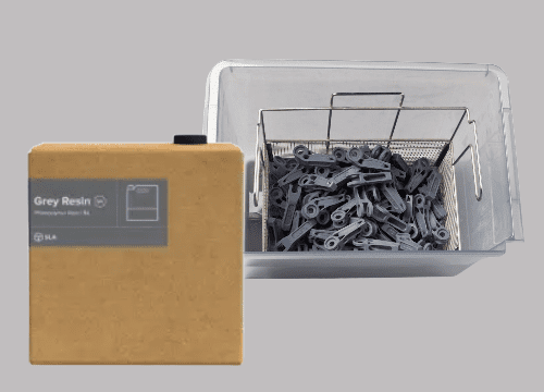 Image shows Formlabs 5-liter resin cartridge or tank and a batch of 3D-printed parts with Grey resin