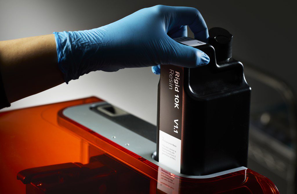 image shows a person inserting Formlabs Rigid 10K V1.1 resin cartridge in the Form 4 mSLA 3D printer