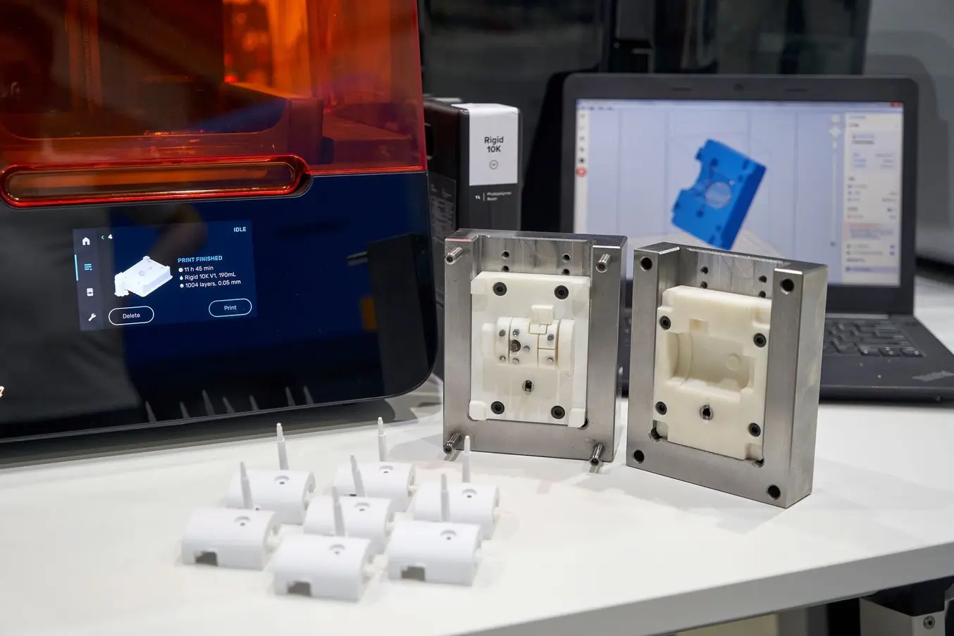 Image shows Formlabs Form 4 printer and 3D printed molded parts
